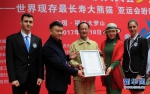 陈玉村和认证官展示“世界上现存最长寿圈养大熊猫”世界纪录证书。新华网 肖和勇 摄 - 新浪