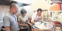 郑长清（左一）和妻子雪贞正在检查免费食堂晚餐的菜肴 - 新浪