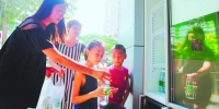 两位放暑假的孩子，在妈妈的引领下用自己的零花钱买来矿泉水为“爱心冰箱”补充能量。 - 新浪