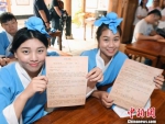 二名身着汉服的台湾学子们在福州正谊书院体验“乡试”并展示试卷。　记者刘可耕 摄 - 福建新闻