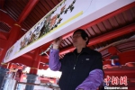 55岁的潘家瑜正在郭氏宗祠横梁上作画，其创新的画法得到师父郭顺忠的赞许。　陈龙山 摄 - 福建新闻