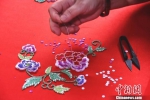 在绣工的穿针引线下，花朵逐渐“绽放”在罗缎上。　陈龙山 摄 - 福建新闻