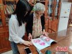 民间剪纸艺术家、国家级非遗传承人袁秀莹向记者介绍她以前创作的作品。叶秋云 摄 - 福建新闻
