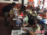 台湾资深设计师曹登贵指导小朋友画图。供图 - 福建新闻