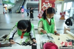 六名小学生现场书写国画赠送旅客。　庄建华 摄 - 福建新闻