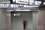 资料图：1月23日，武汉地铁暂停运营，一名工作人员在拉下的门帘上粘贴公告。中新社记者 张畅 摄 - 新浪