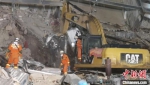 3月11日5时30分左右，挖掘机在坍塌废墟的中部区域挖出一辆完全变形的汽车残骸，隐约可见白色车身。　孙虹 摄 - 福建新闻