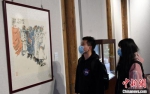 二名青年观看“守望相助 万众一心——抗疫艺术作品展”。　记者刘可耕 摄 - 福建新闻