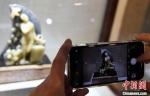 由中国工艺美术大师郑幼林创作的寿山石雕作品《天使归来》，吸引观众用手机拍照。　记者刘可耕 摄 - 福建新闻