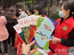 巾帼志愿者向社区居民发放宣传手册。 - 福建新闻